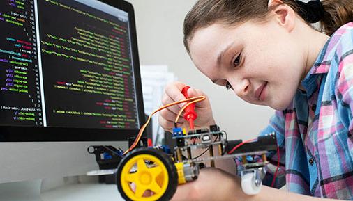 Young girl working on computer and robot
